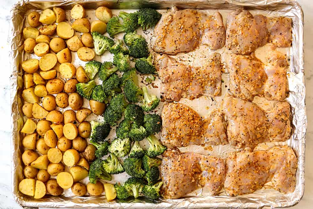 showing how to make lemon garlic chicken recipe by lining chicken thighs, broccoli and potatoes on a sheet pan to bake in the oven