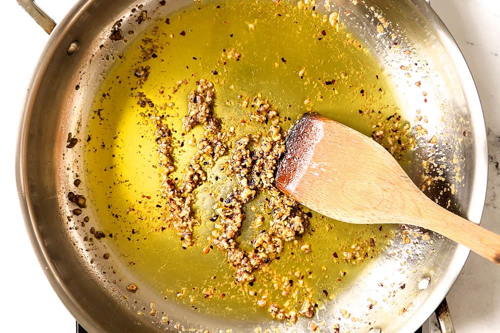 showing how to make Puttanesca recipe by sautéing the garlic, red pepper flakes and anchovies in olive oil