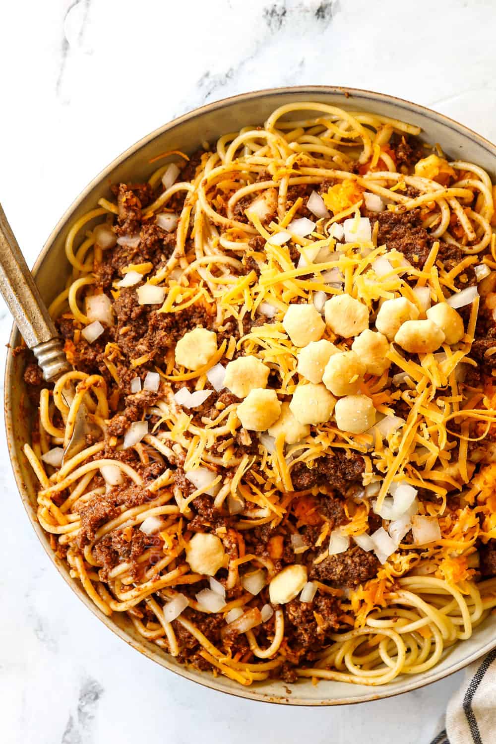 top view of Cincinnati chili served in a bowl over spaghetti with onions and cheese