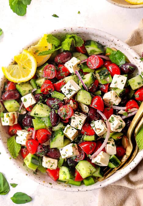 top view of showing how to make Greek Salad recipe by mixing tomatoes, cucumbers, Kalamata olives, red onions and feta together
