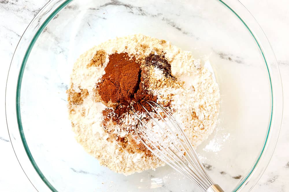 showing how to make pumpkin pancakes by whisking the flour, cinnamon, ground ginger, cloves, nutmeg, baking powder and baking soda together in a bowl