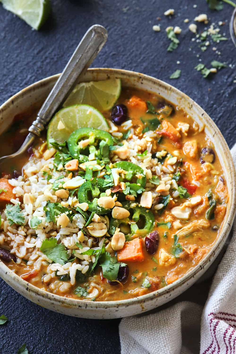 showing how to serve African Peanut Stew by topping with rice, cilantro, peanuts and lime juice