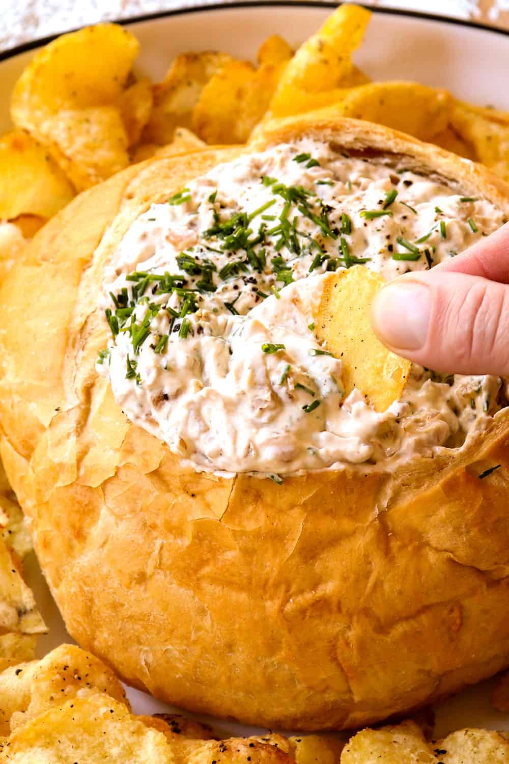 up close of dipping a chip into French Onion Dip