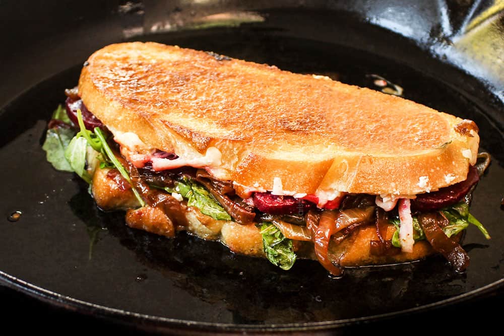 showing how to make gourmet grilled cheese by toasting in a cast iron skillet