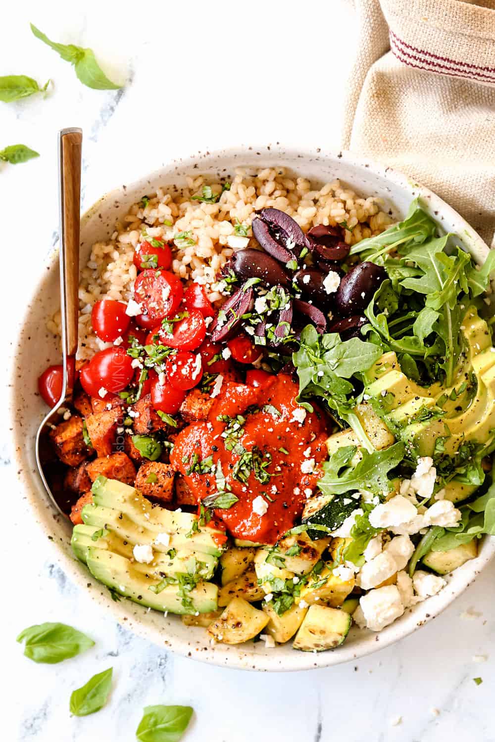 top view showing how to use roasted red pepper sauce by adding it to a Mediterranean bowl