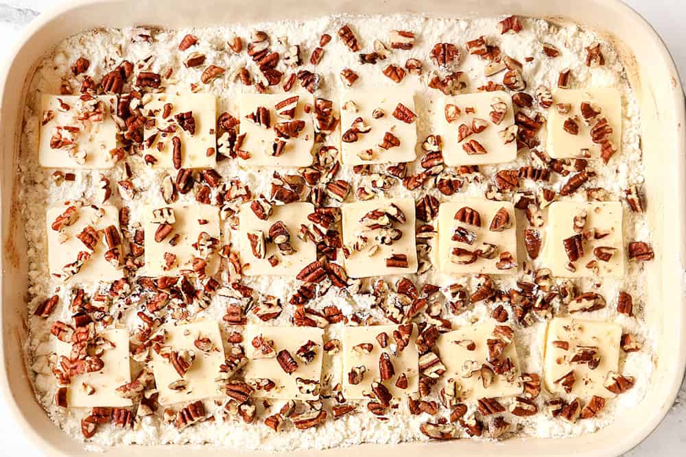 showing how to make apple dump cake recipe by adding thinly sliced pads of butter on top of the cake mix followed by pecans
