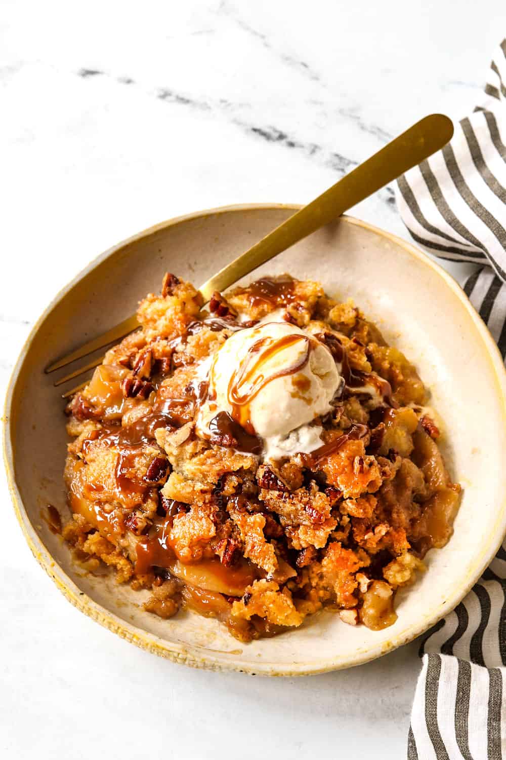showing how to serve apple dump cake by adding it to a plate with caramel and ice cream