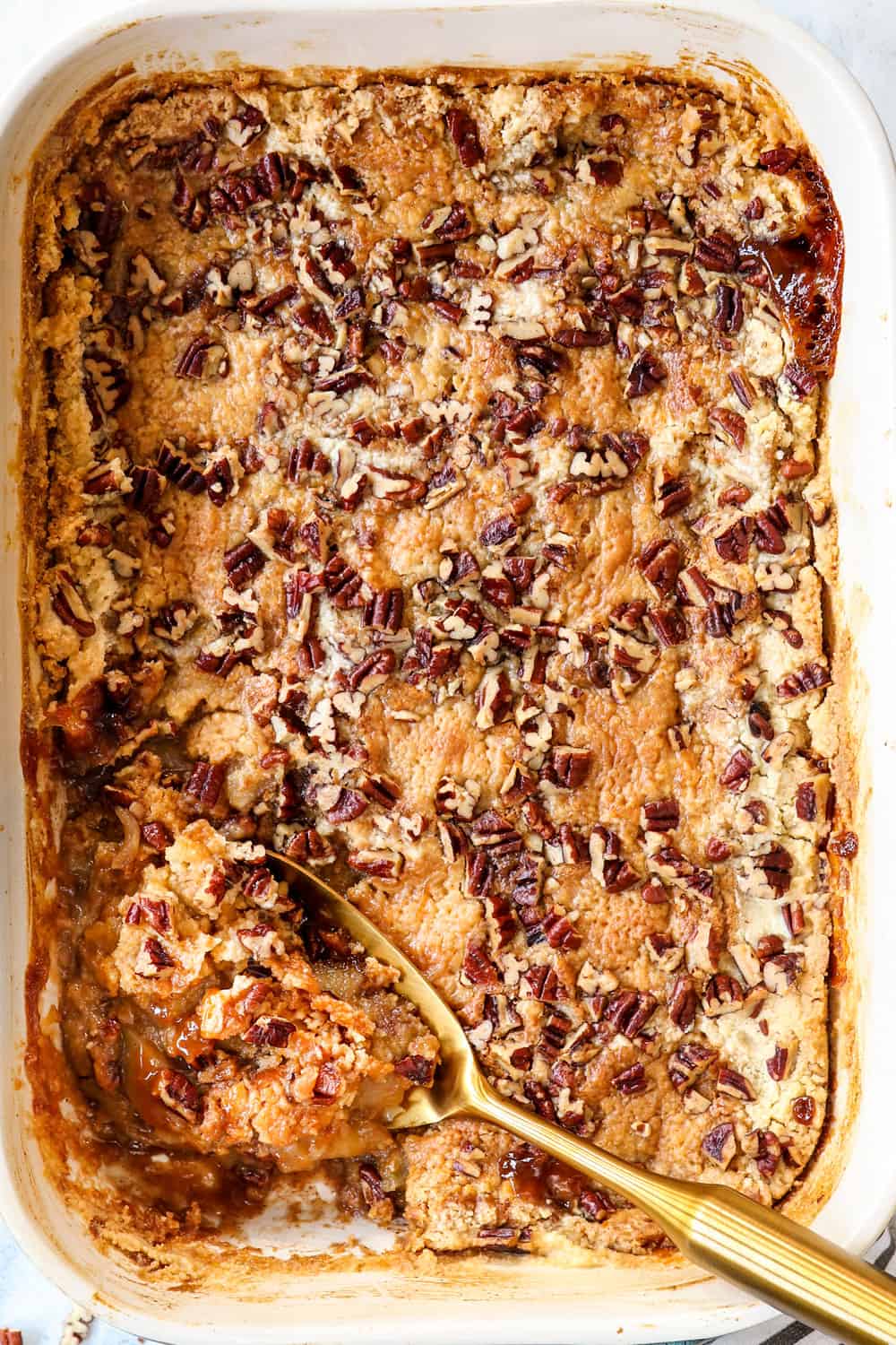 top view of apple dump cake recipe in a baking pan with a serving spoon