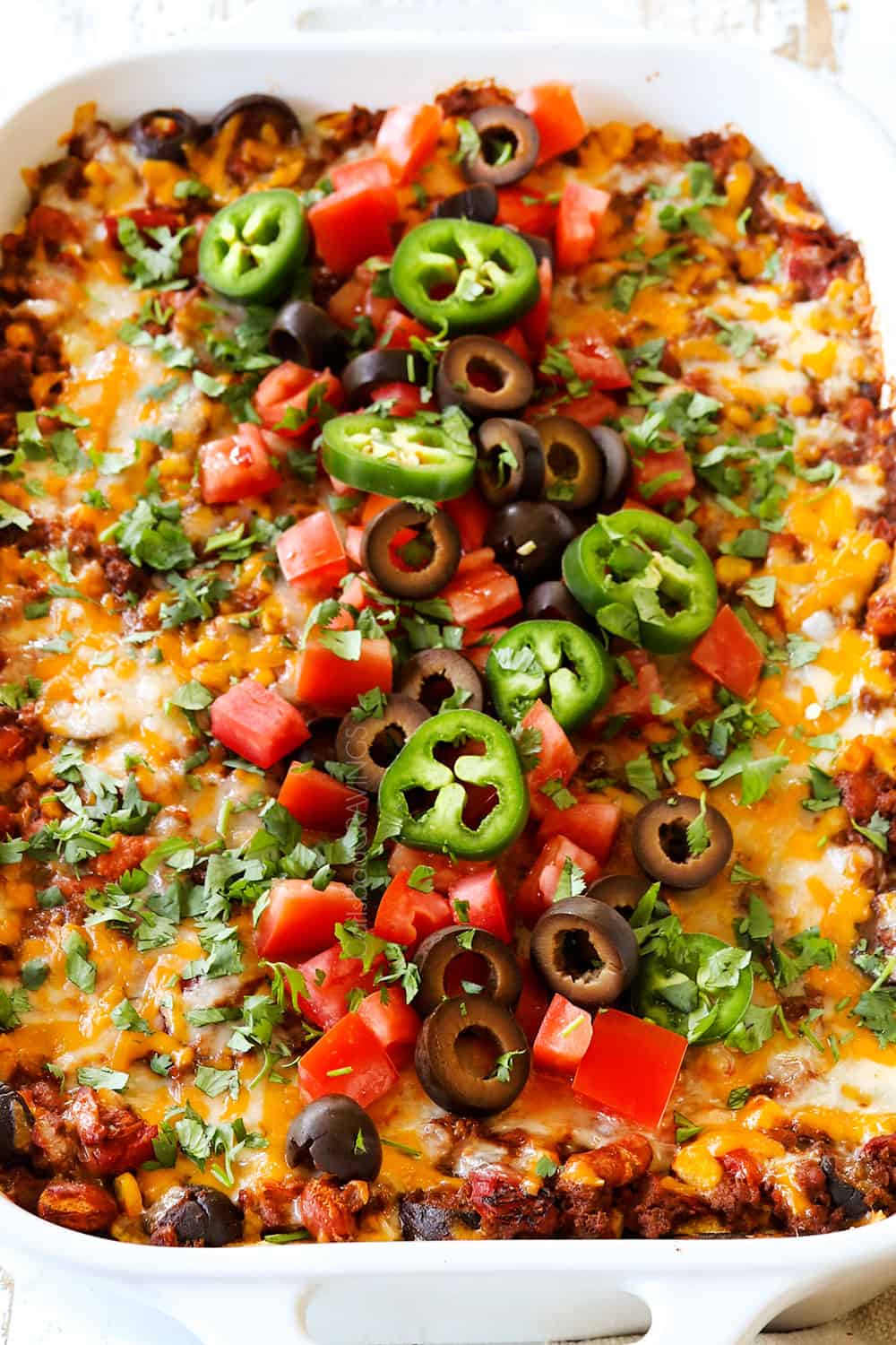showing how to make beef enchilada casserole recipe by baking in the oven until cheese is melted