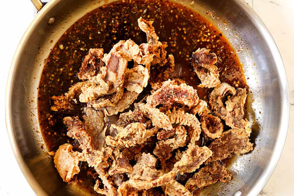 showing how to make ginger beef by adding the fried beef to the sauce in the skillet