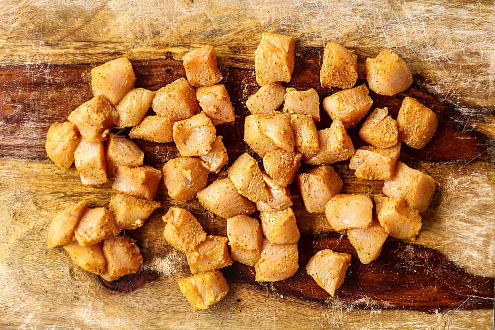 showing how to make peanut noodles recipe by seasoning the chicken with garlic powder, ginger powder, coriander, salt and pepper
