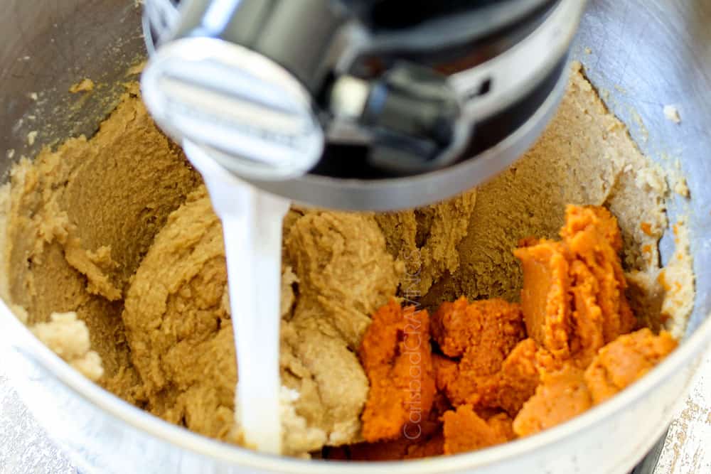 showing how to make pumpkin oatmeal cookies by adding pumpkin puree, vanilla and egg yolk to the mixer