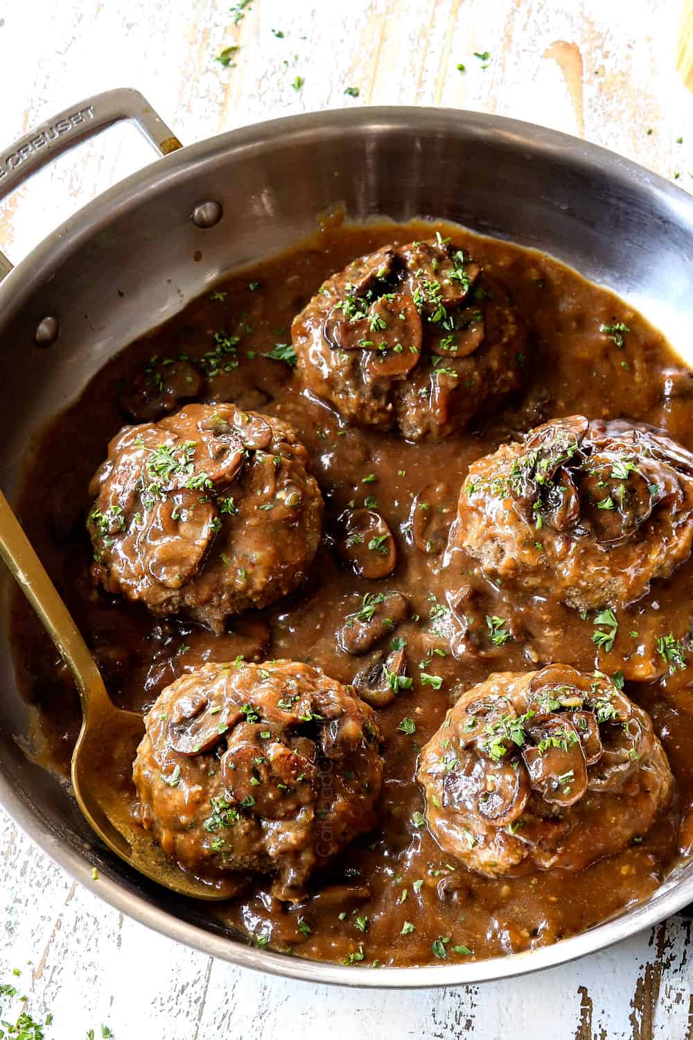 homemade Salisbury steak in a stainless steel skillet with brown gravy