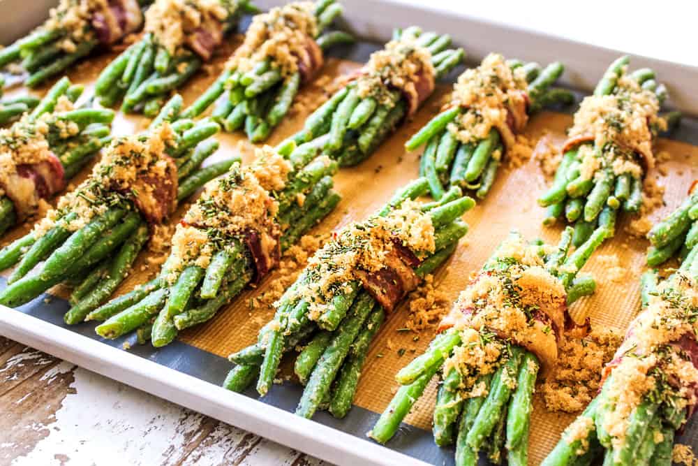 showing how to make bacon wrapped green beans by adding brown sugar to the top of the bundles before baking