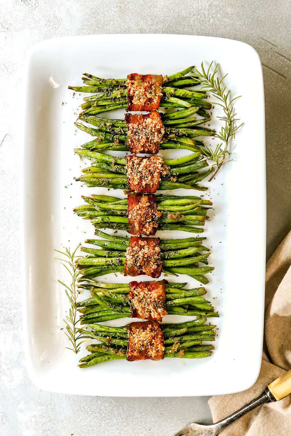 top view of bacon wrapped green beans on a white platter