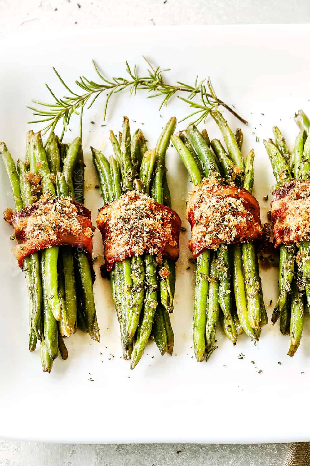 up close of bacon wrapped green beans garnished with rosemary