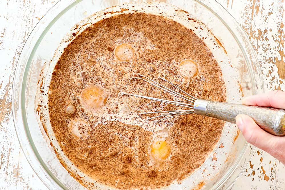 showing how to make apple bread pudding by whisking eggs, half and half, cinnamon and sugar together in a bowl