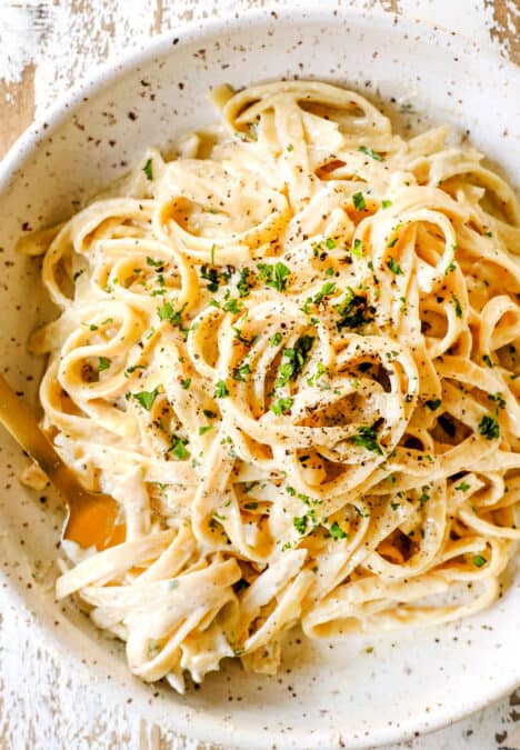 top view of fettuccine Alfredo in a bowl with freshly cracked pepper showing how creamy it is