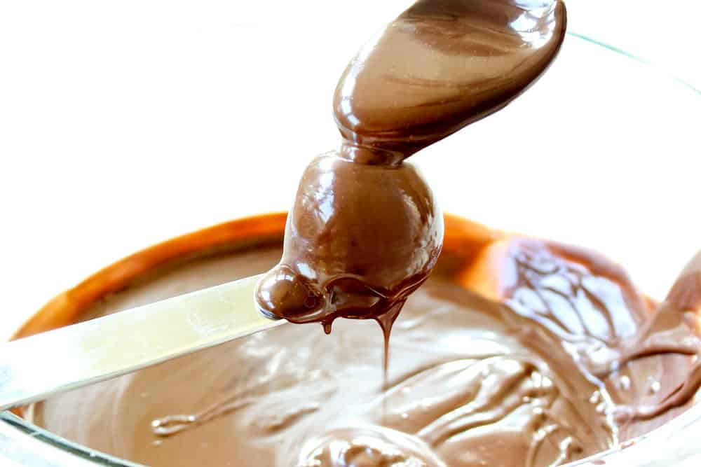 showing how to make Oreo Truffle Recipe by spooning chocolate over the Oreo Balls balancing on a knife