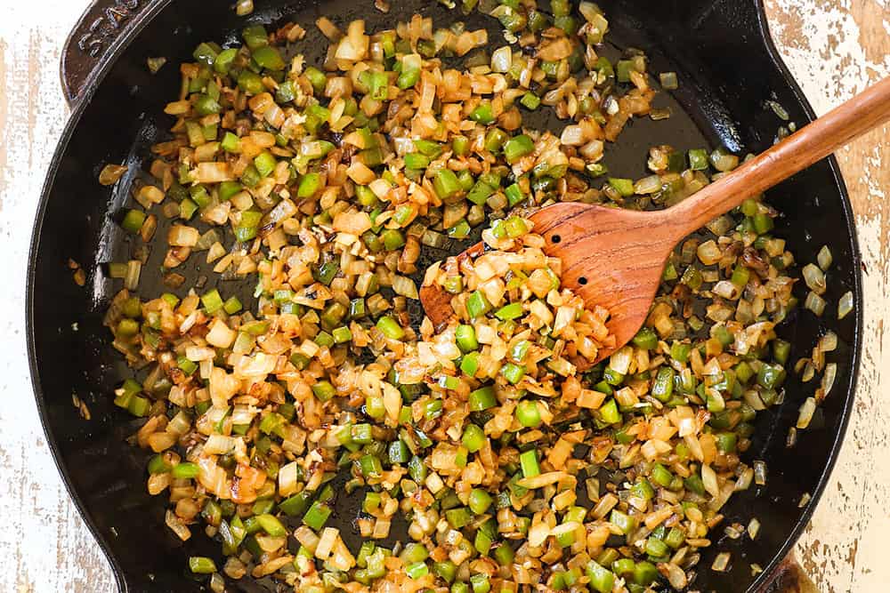 showing how to make Philly cheesesteak dip by sautéing onions and bell peppers in a skillet
