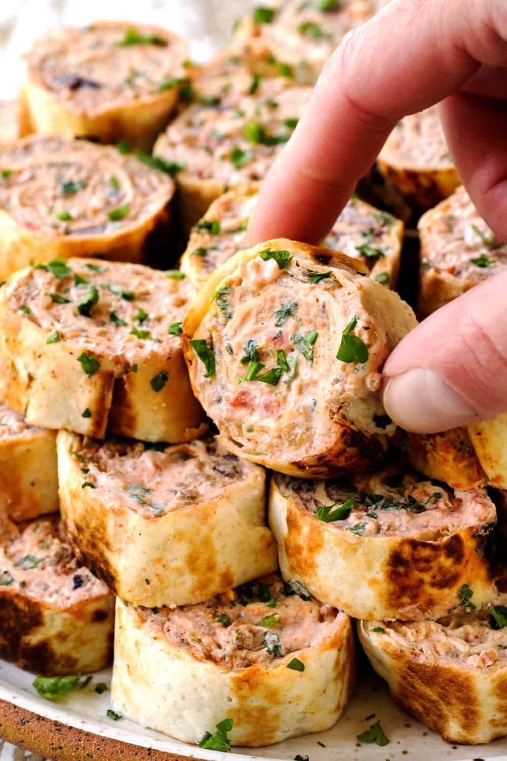 a stack of pinwheel appetizers stacked on a platter garnished with cilantro