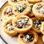 a stack of mini quiche on a plate showing how flaky the crust is