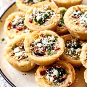 a stack of mini quiche on a plate showing how flaky the crust is