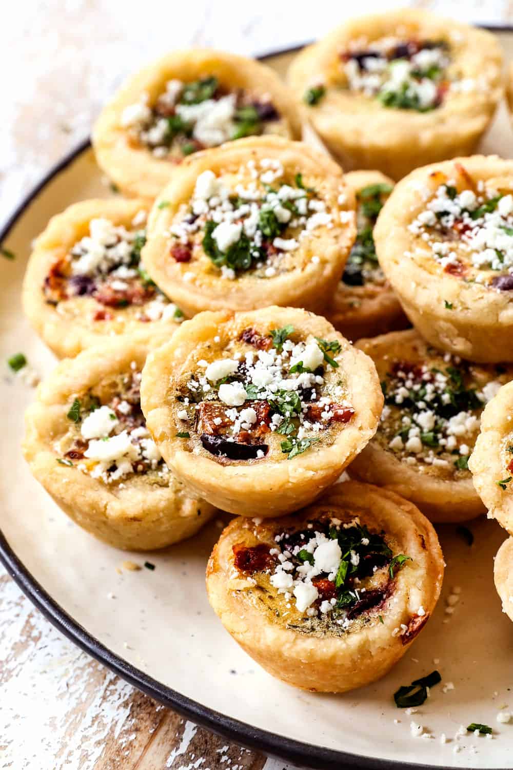 a stack of mini quiche on a plate showing how flaky the crust is