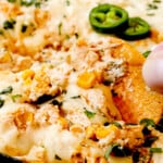 up close of scooping up hot corn dip recipe with corn, jalapenos and cilantro