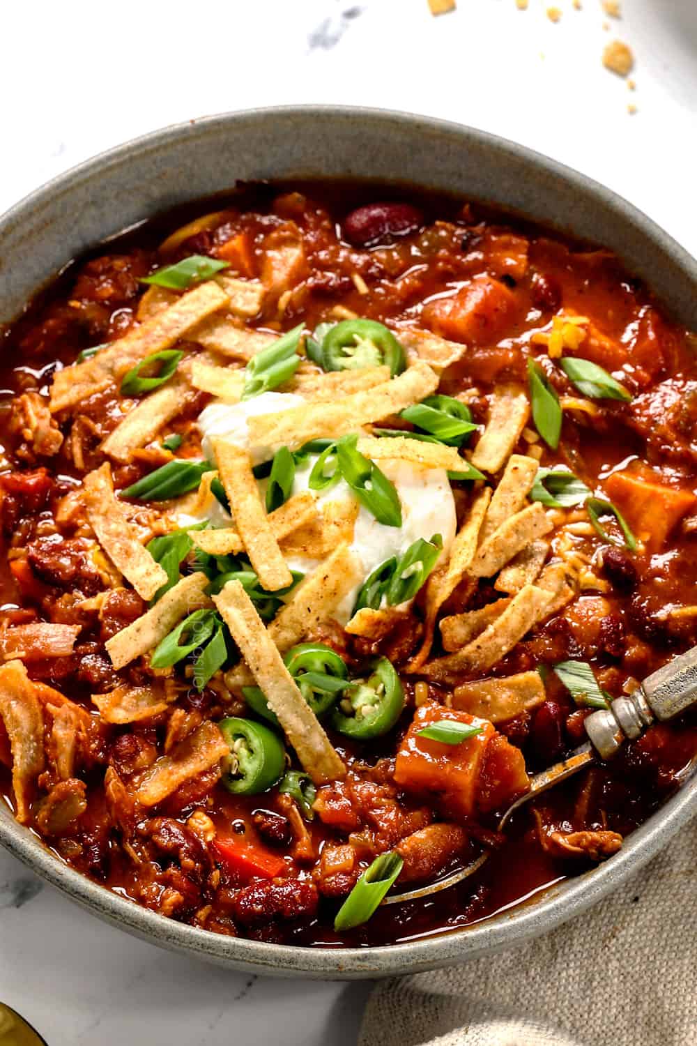 up close of a bowl of chicken chili recipe digging in with a spoon