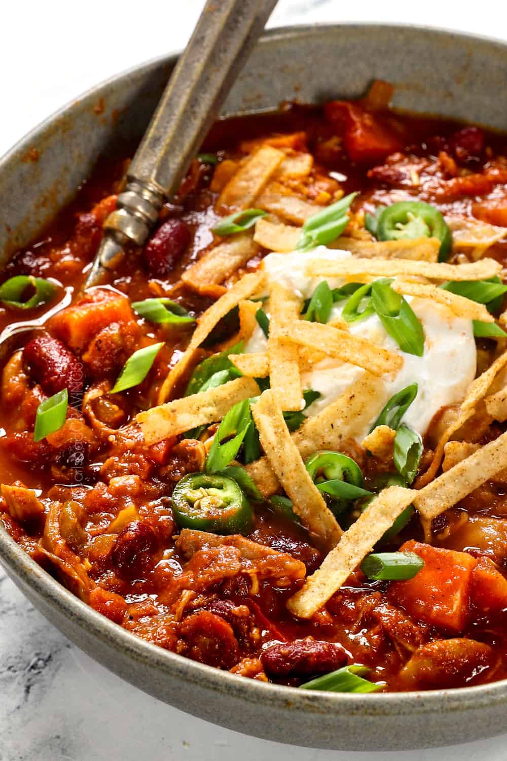 up close of easy healthy chicken chili recipe topped with sour cream and green onions