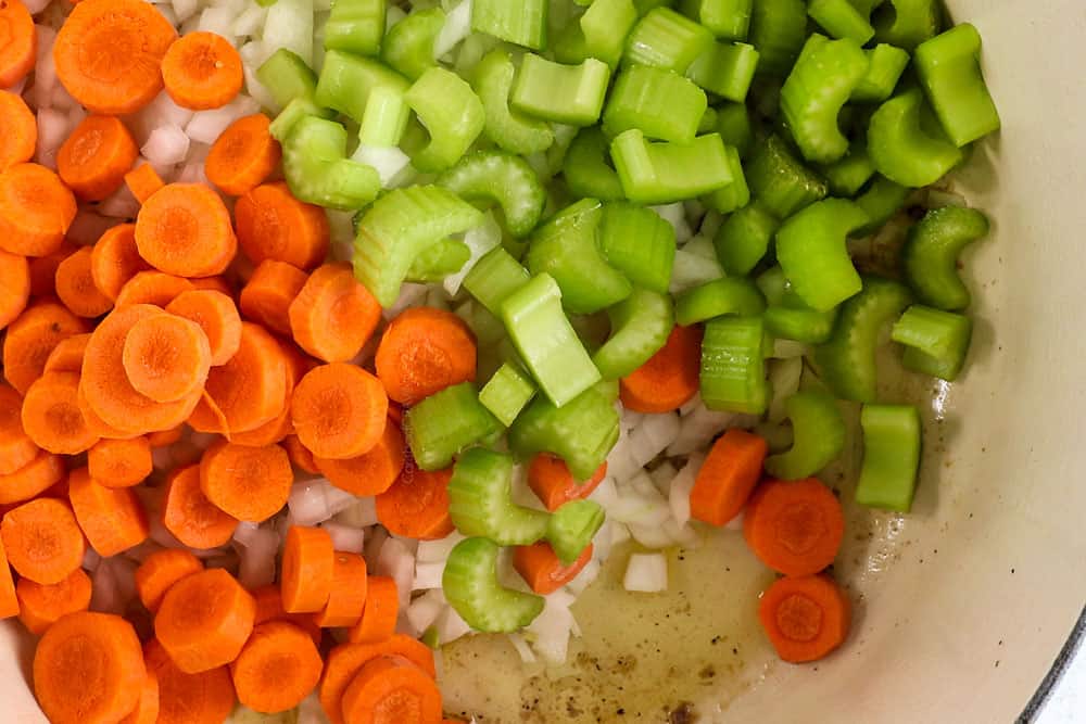 showing how to make creamy chicken noodle soup by cooking onions, carrots and celery in a Dutch oven