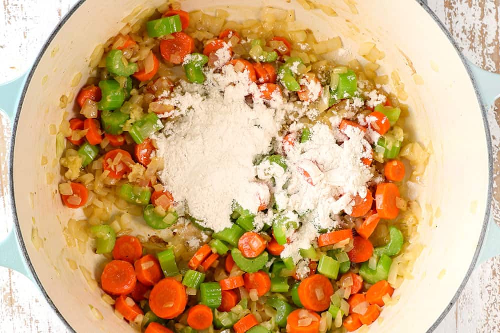showing how to make easy creamy chicken noodle soup recipe by adding flour to the vegetables in order to thicken the soup