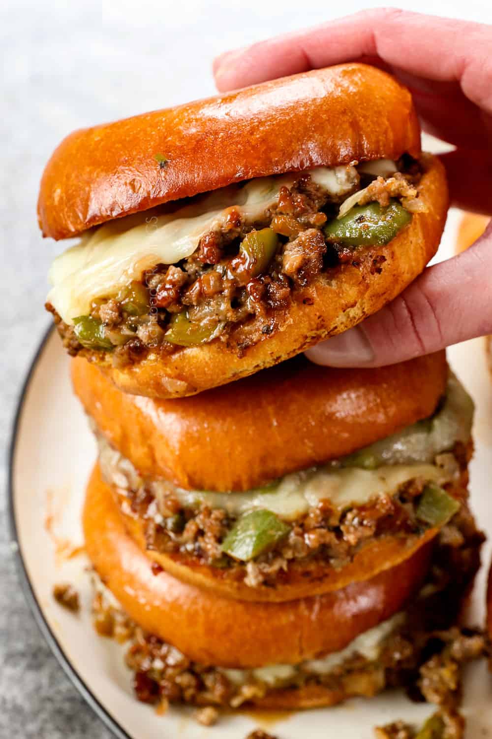 a stack of Philly Cheesesteak Sloppy Joes with provolone cheese in toasted brioche buns
