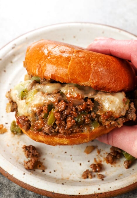 a hand holding Philly Cheesesteak Sloppy Joe showing the melted cheese and saucy filling
