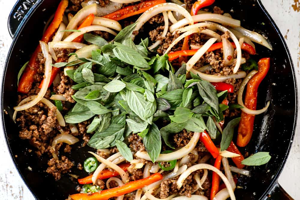 showing how to make Thai Basil Beef (pad krapow) by adding Thai basil to the stir fry