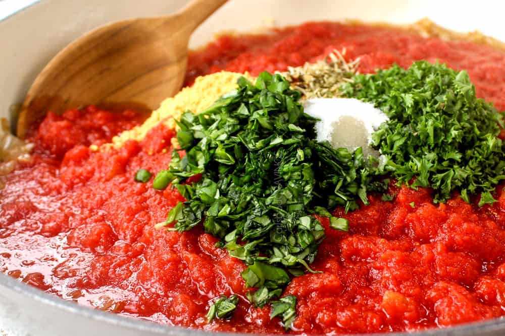 showing how to make tomato sauce by adding basil, parsley, thyme, oregano and rosemary to the crushed tomatoes in the pan