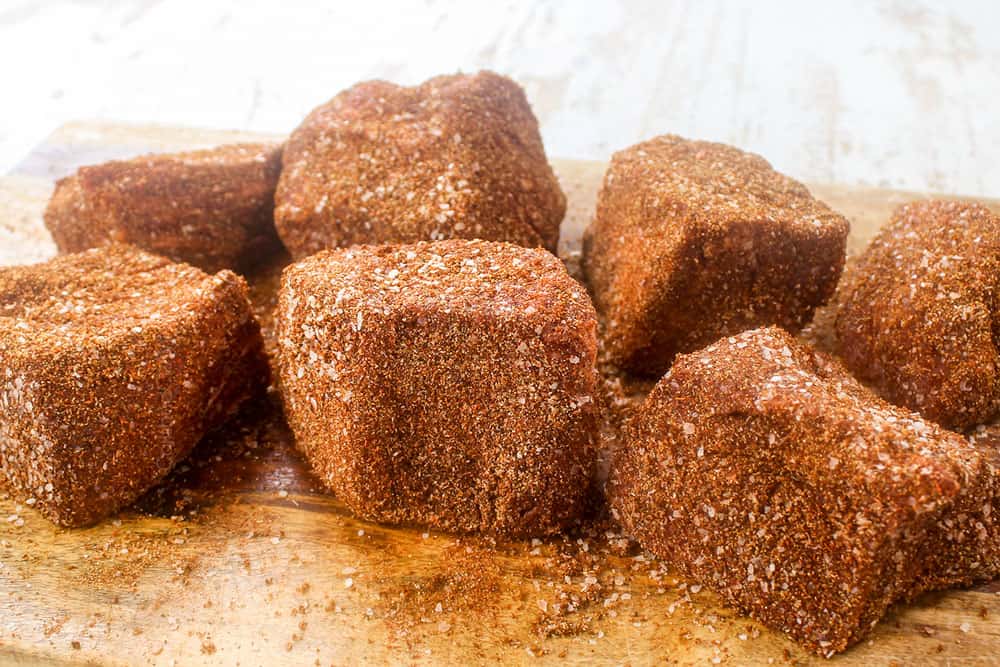 showing how to make beef taco recipe by seasoning the chuck roast with Mexican spice rub on a cutting board