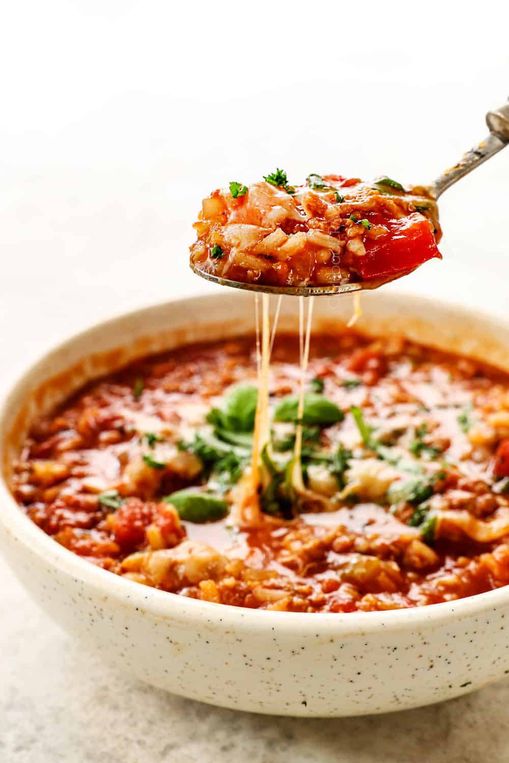 pulling up a spoonful of stuffed bell pepper soup showing how cheesy it is