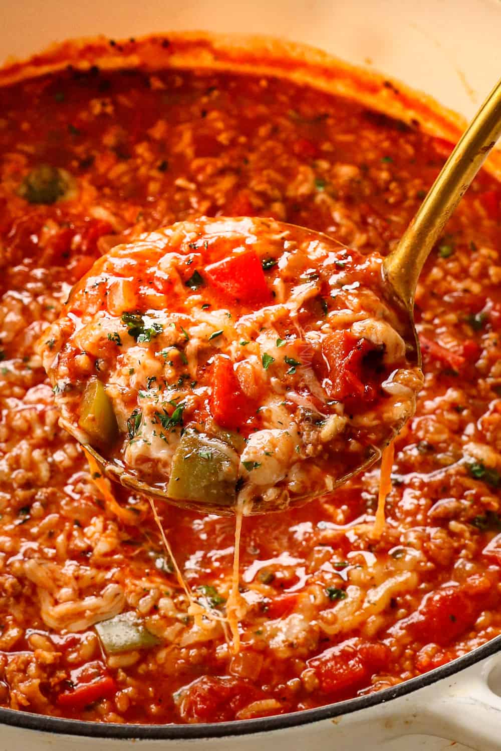 a ladle of stuffed pepper soup recipe with red and green bell peppers, Italian sausage and rice