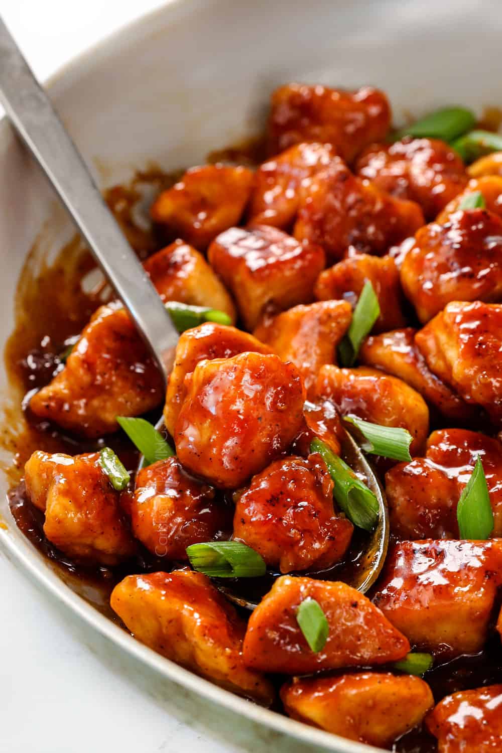 up close of scooping up apricot chicken showing the juicy, plump chicken coated in sauce