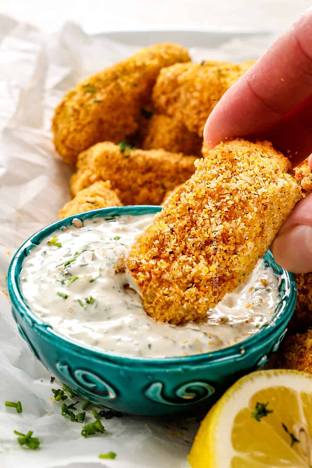 showing how to serve fish sticks by dipping a fish stick in tartar sauce