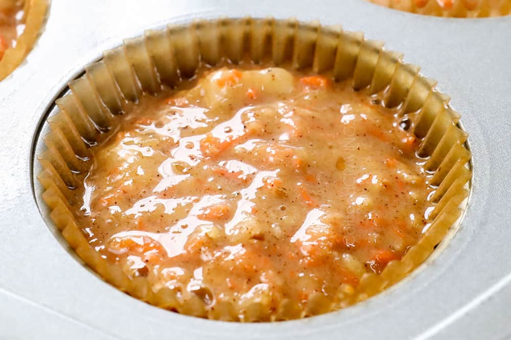 showing how to make carrot cake cupcakes by adding batter to cupcake liners