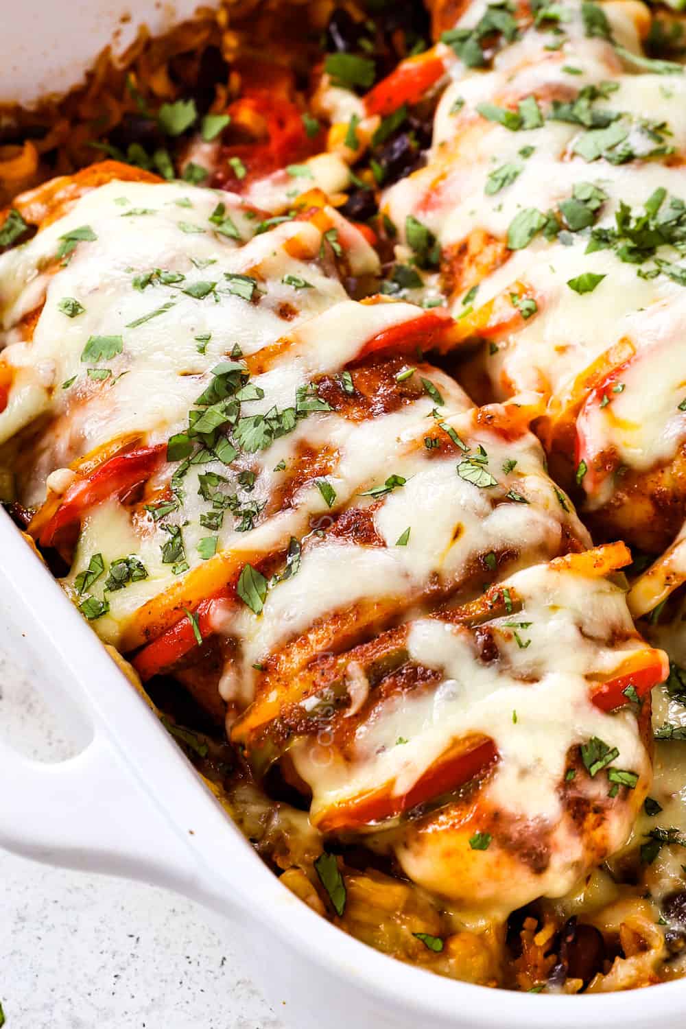 up close of Hasselback chicken showing how to stuff the slits with bell peppers and onions