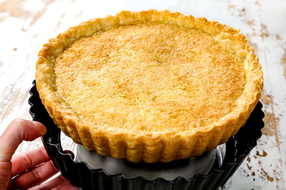 showing how to make coconut pie recipe by removing pie from removable bottom pan