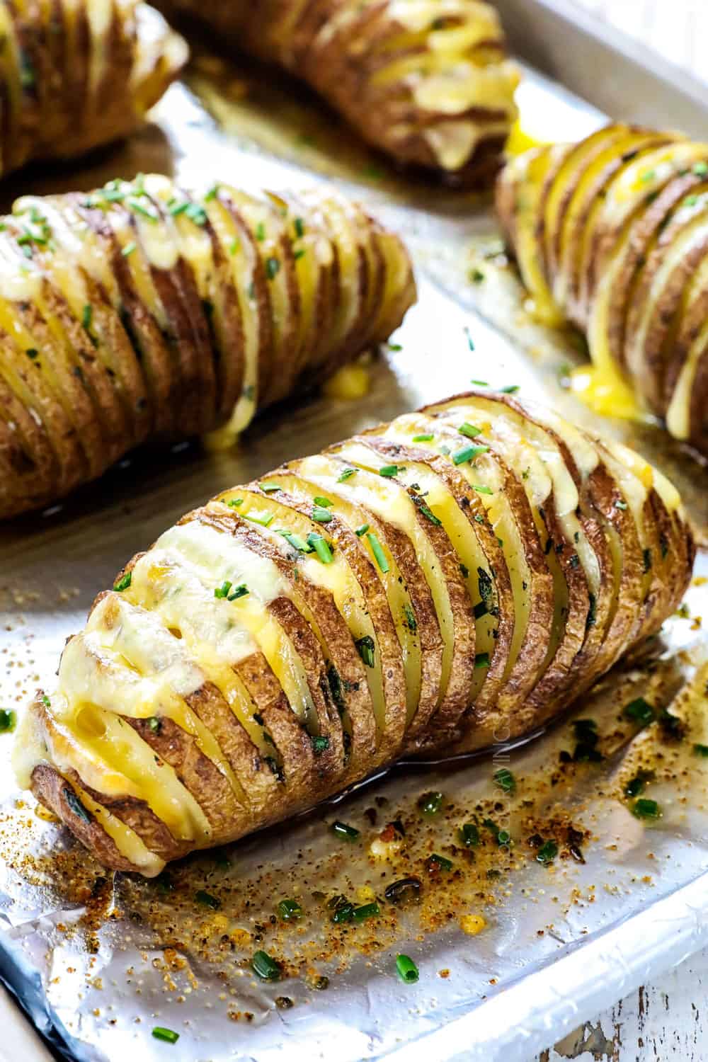 showing how to make Hasselback potato recipe by baking potatoes by garnishing with chives