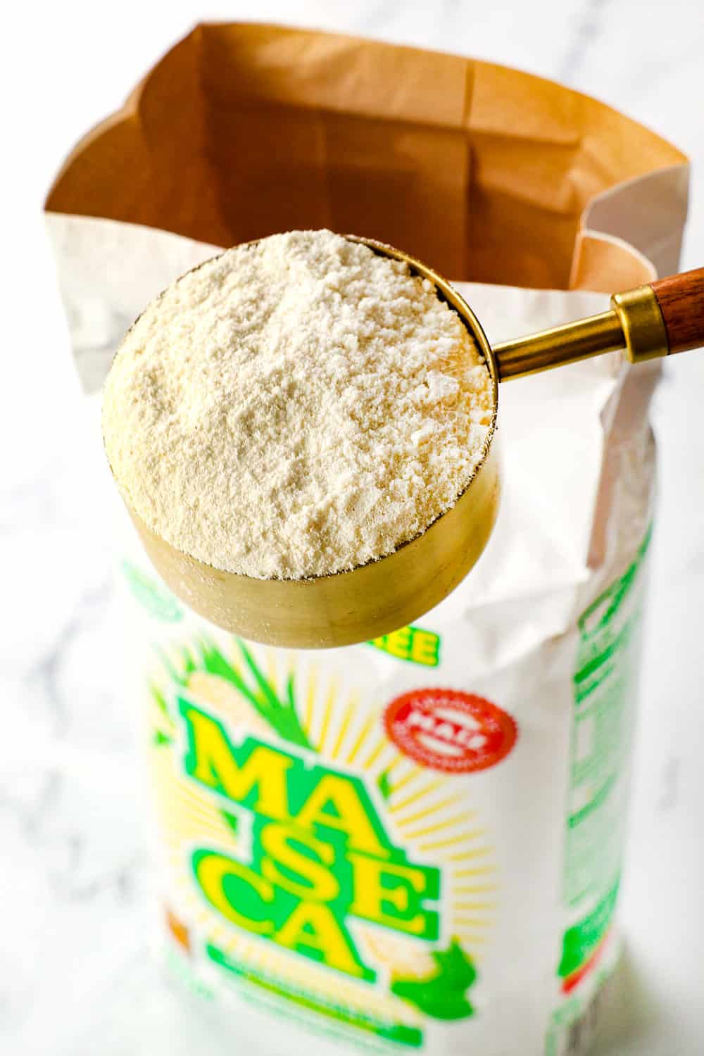 showing how to make Mexican Tamales recipe with masa harina by scooping masa harina in a measuring cup