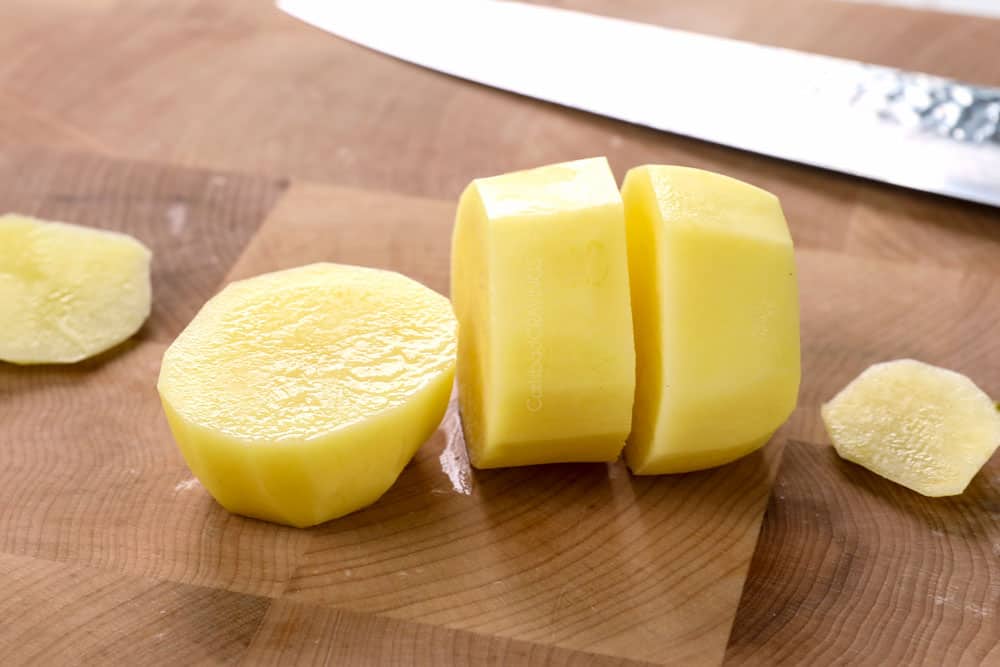 showing how to make melting potatoes recipe by slicing peeled Yukon gold potatoes into 1 inch slices