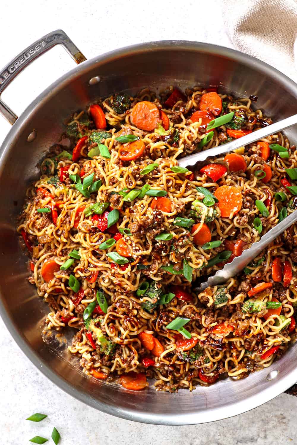 top view of ramen noodles stir fried with ground beef, carrots, bell peppers in a stainless steel skillet