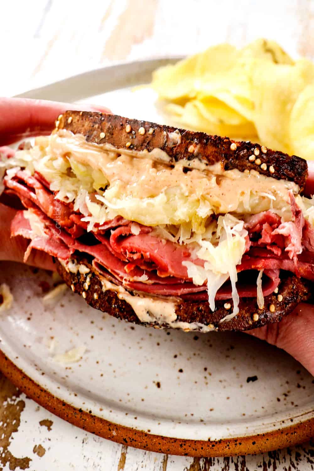 picking up a Reuben sandwich to eat